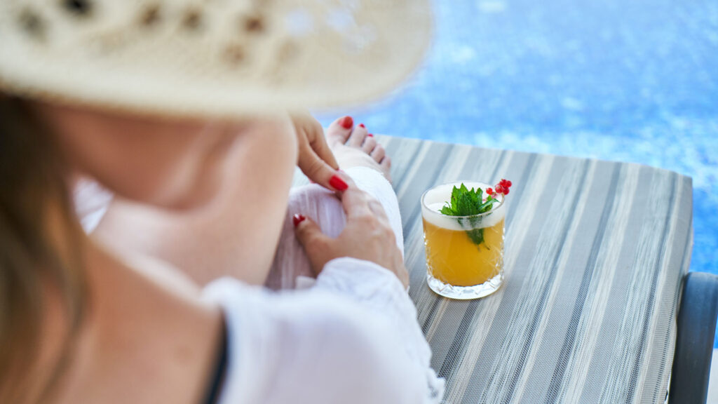 woman relaxing poolside with beverage