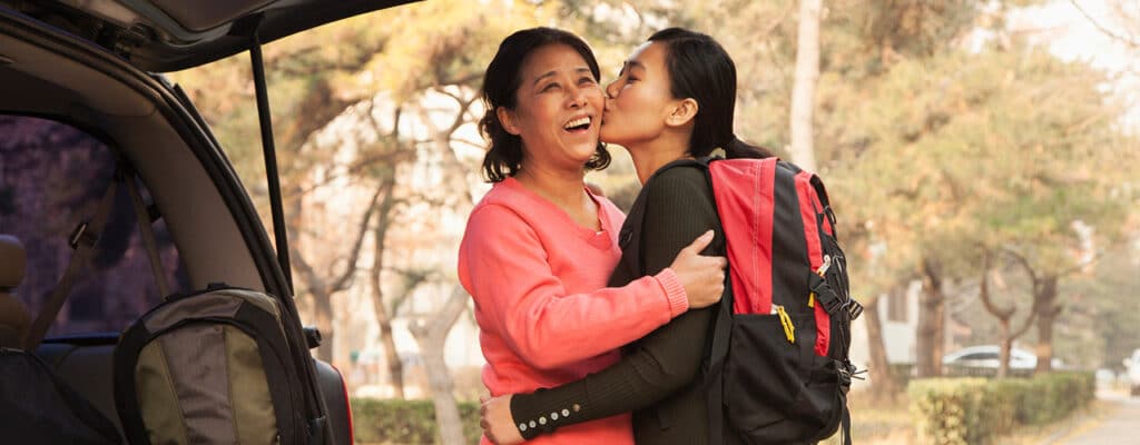 mom gets a kiss from her daughter at college drop off