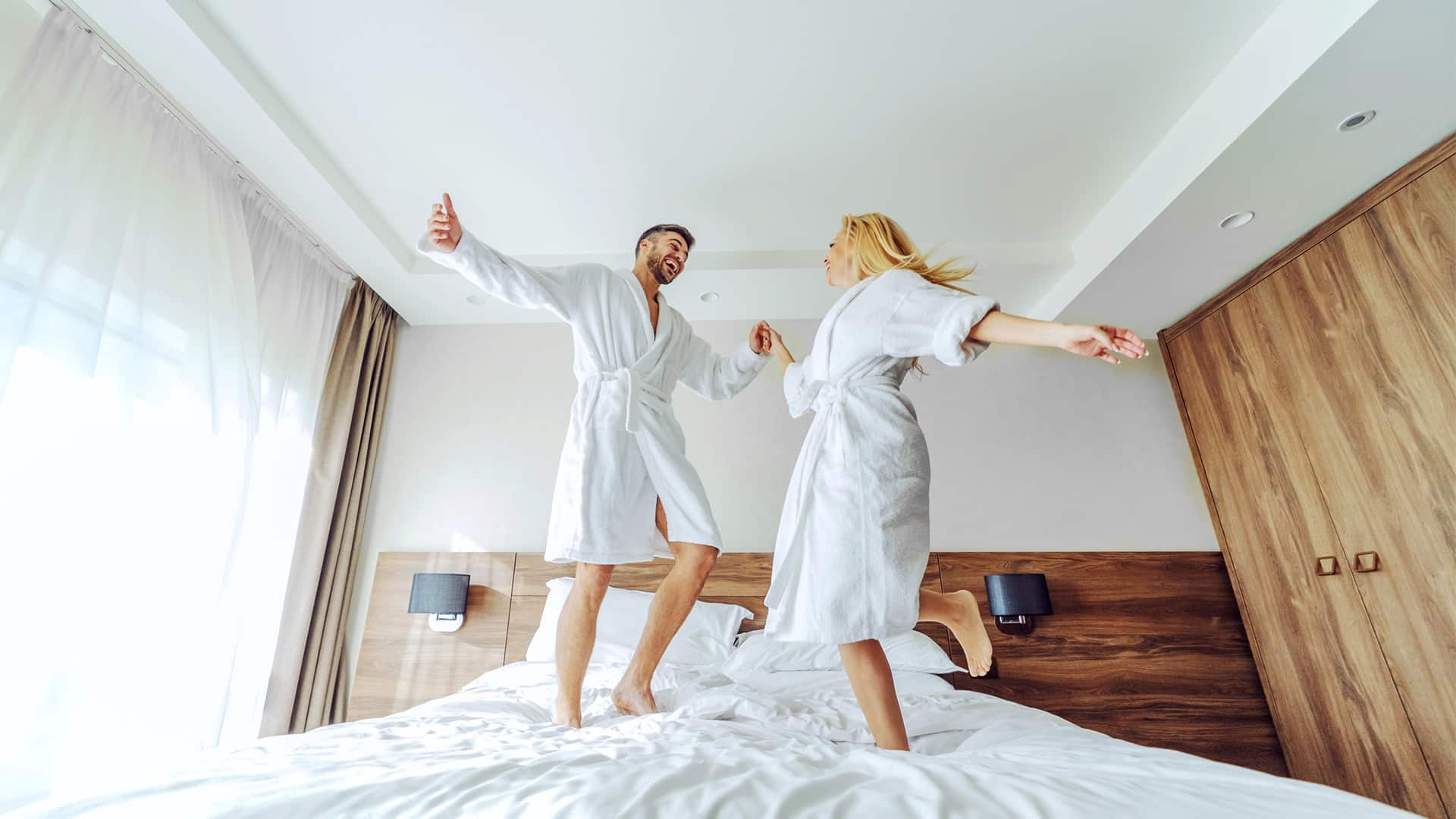 couple dancing on hotel bed in bathrobes