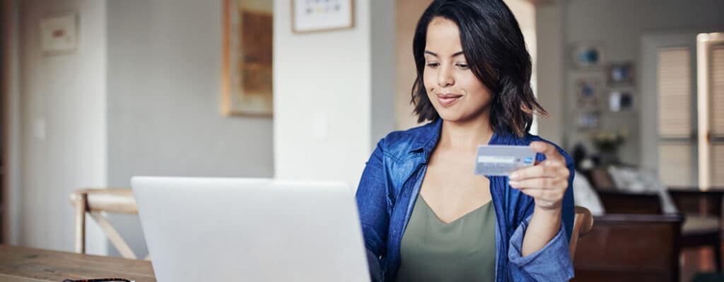 woman on computer holding credit card