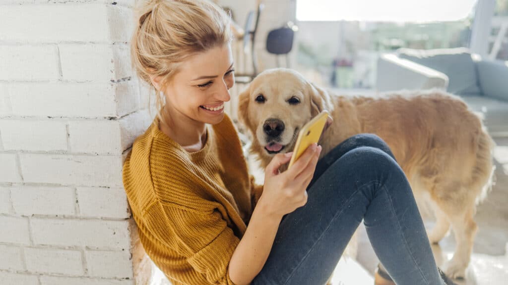 woman sitting on floor with dog looking at phone