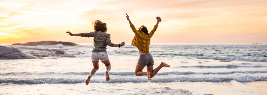 two friends jumping on the beach