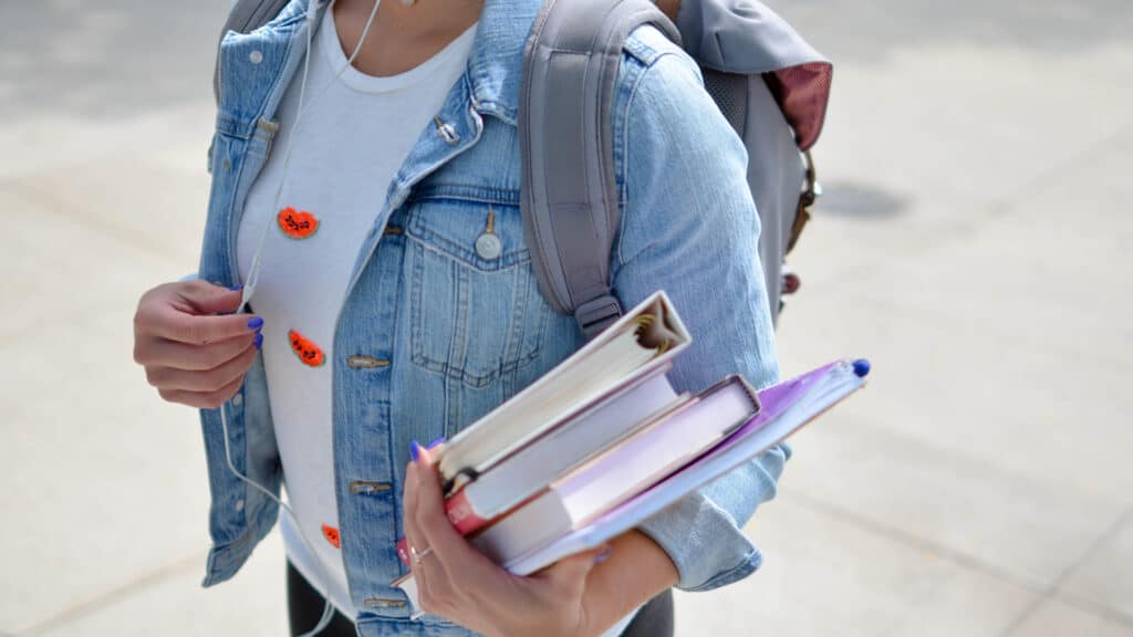 student holding books on college campus