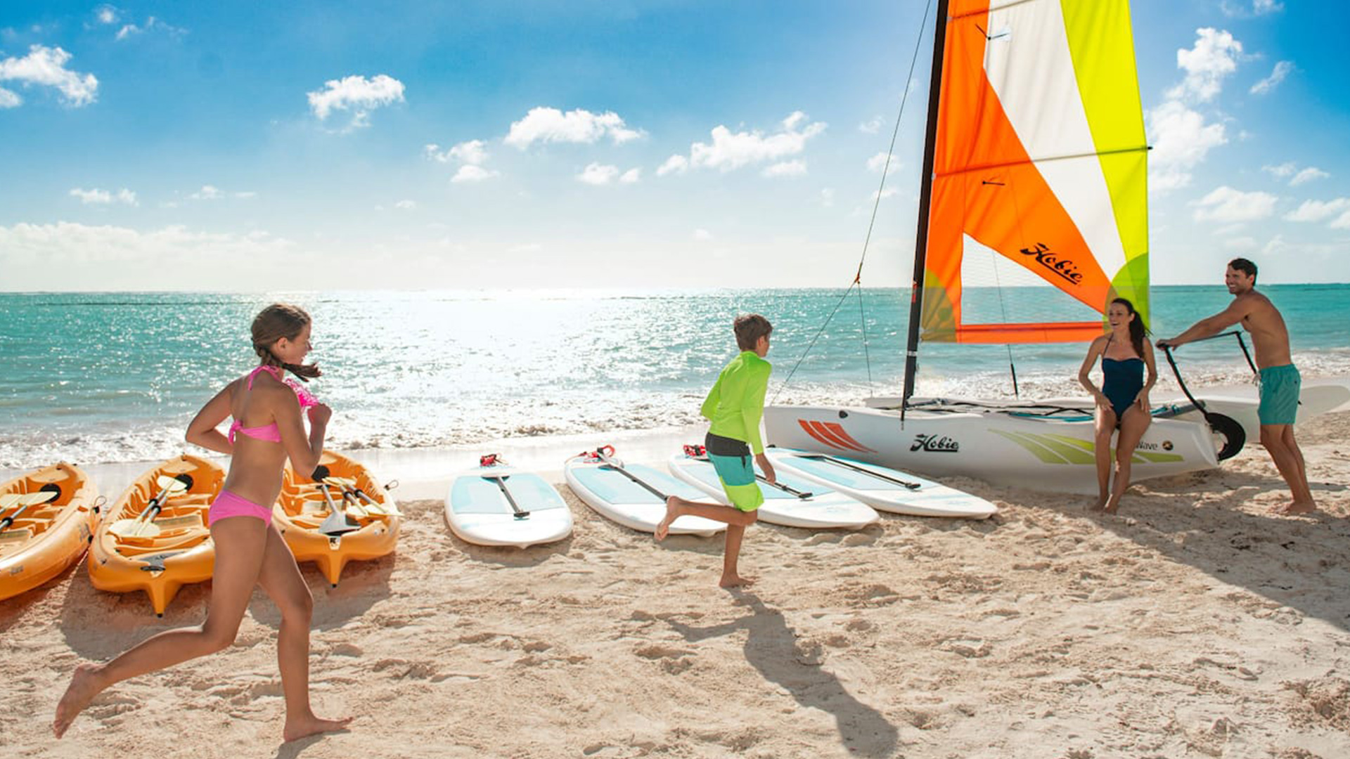 family playing on beach near sailboats at Hyatt Ziva Cap Cana