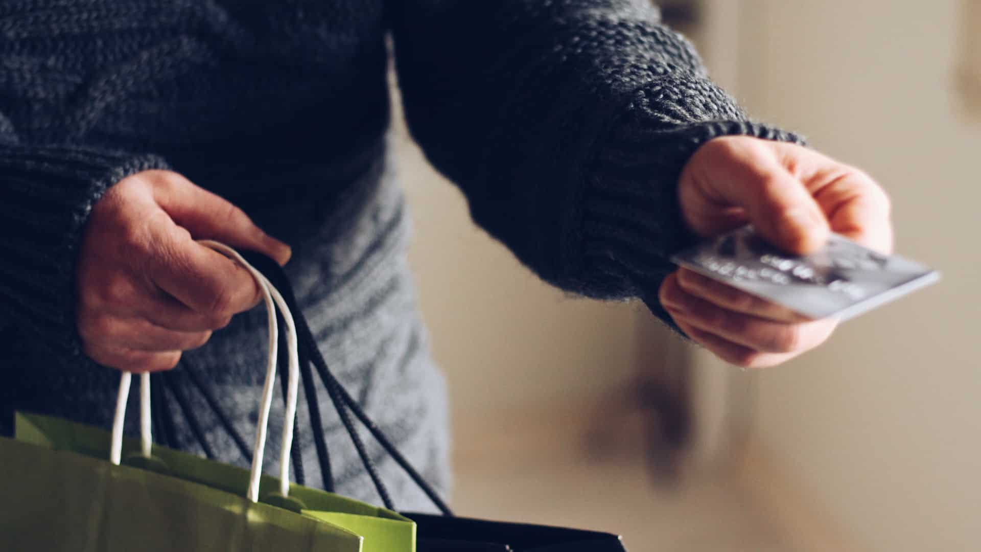paying with debit card holding shopping bags