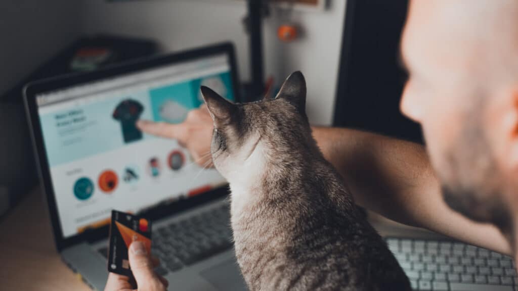 man shopping online with credit card and cat