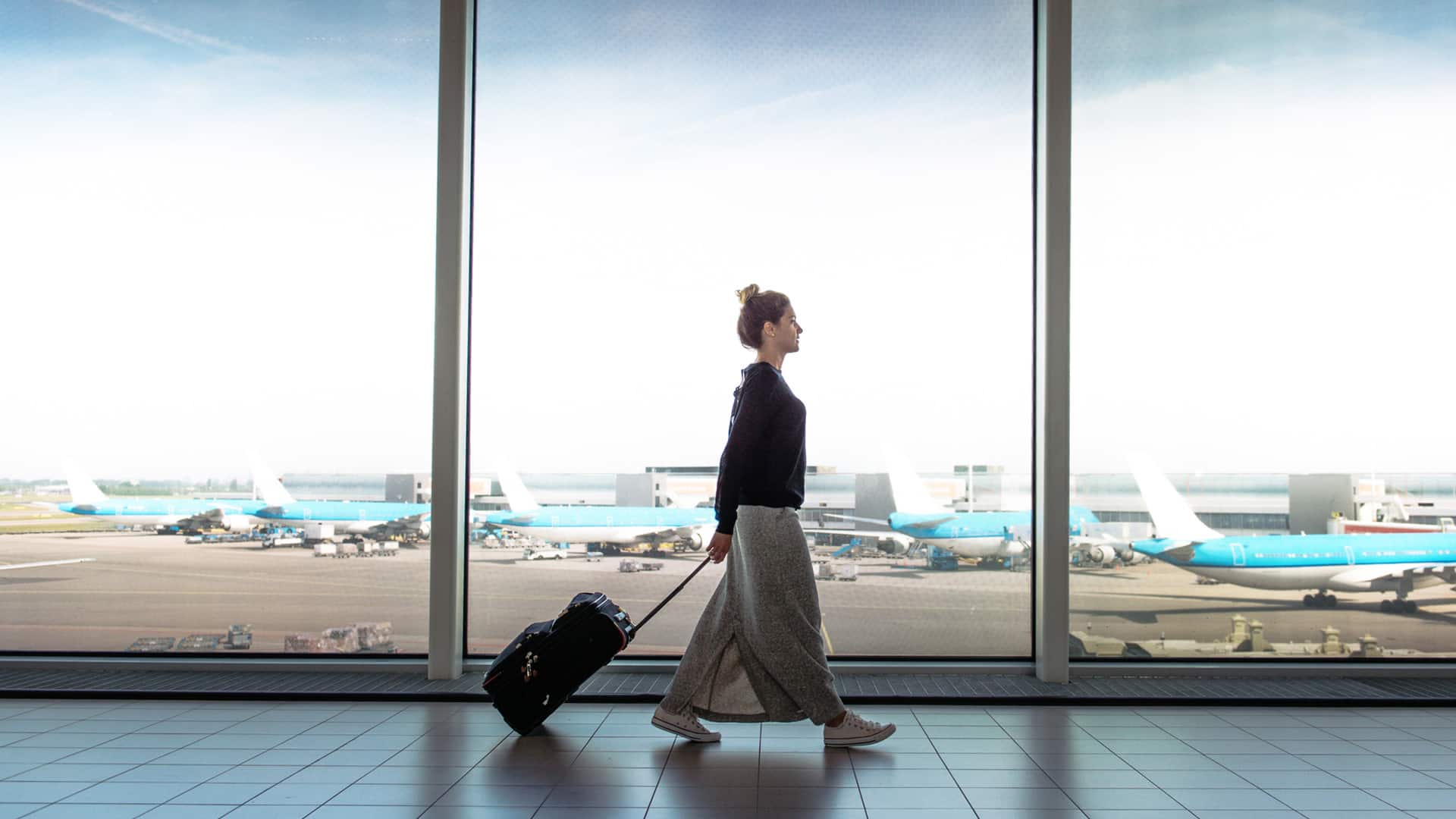 woman with suitcase walking through airport