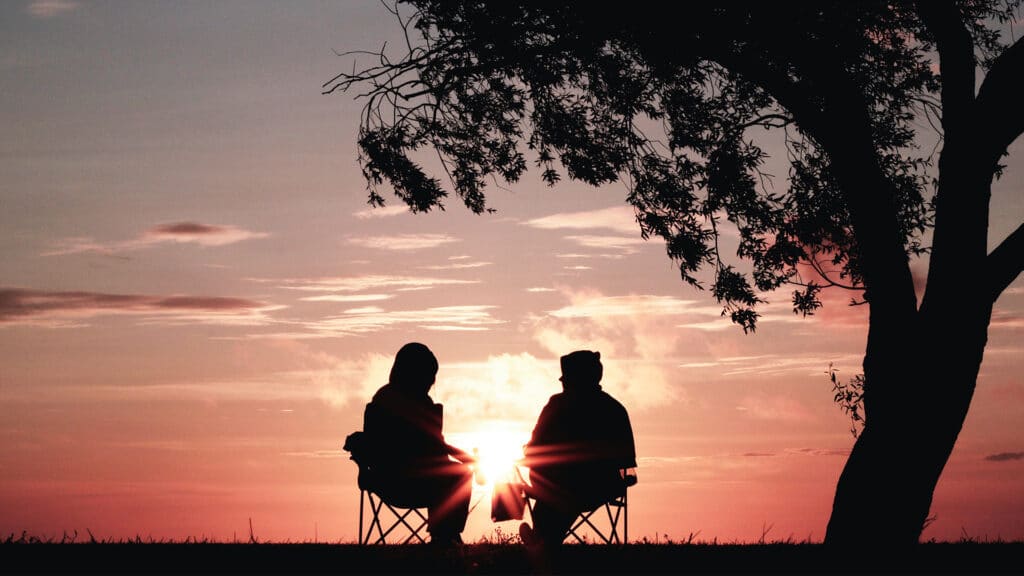 retired couple sitting outside at sunset