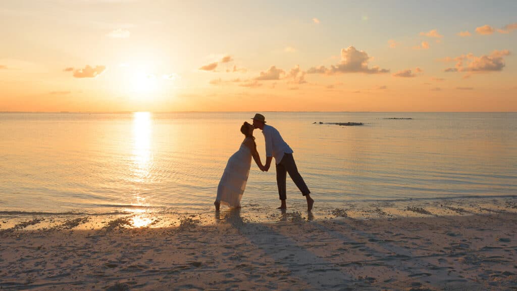 Couple kissing on beach during honeymoon
