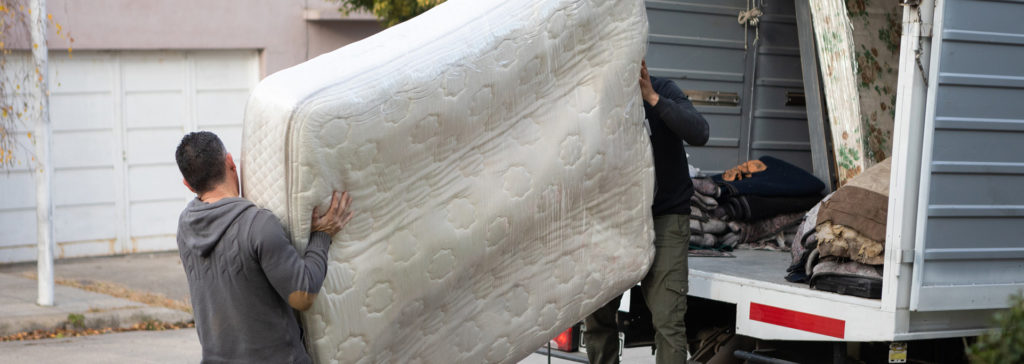two men moving mattress into moving truck