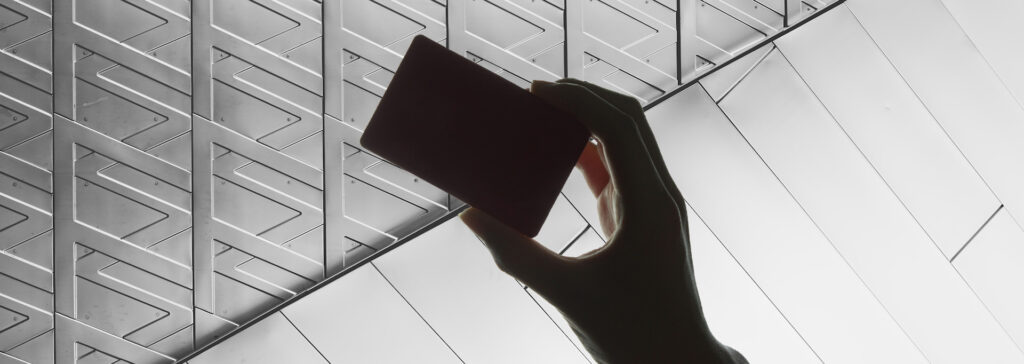 silhouette of hand holding credit card over metal background
