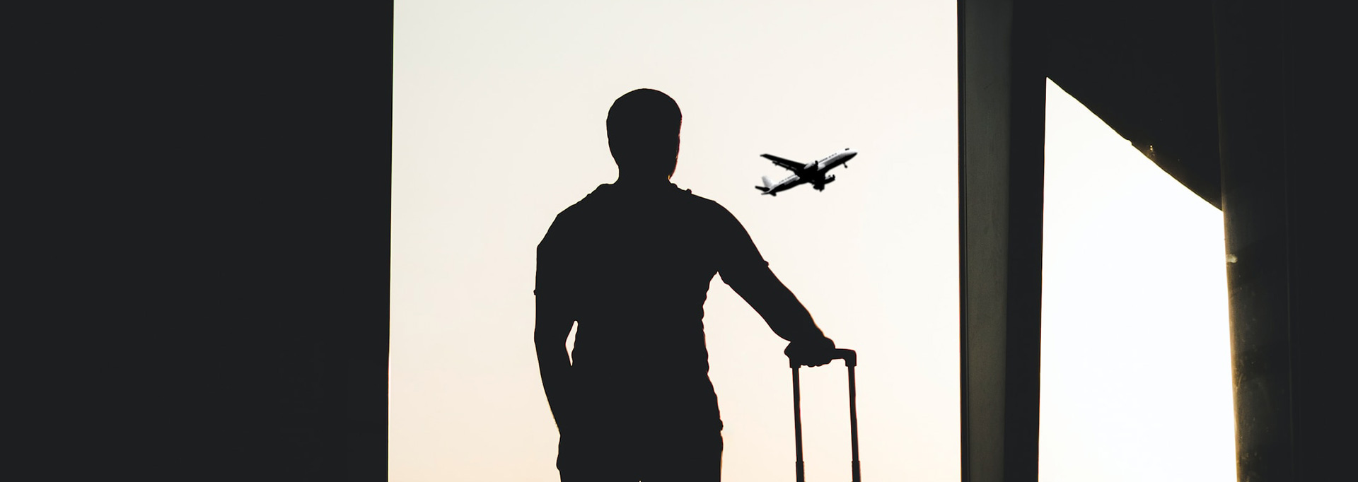 silhouette of man standing in airport looking at airplanes