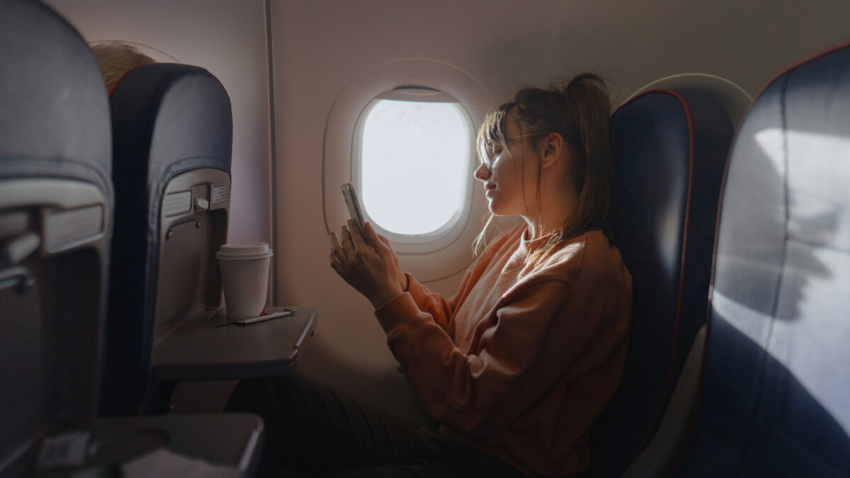woman on airplane checking phone