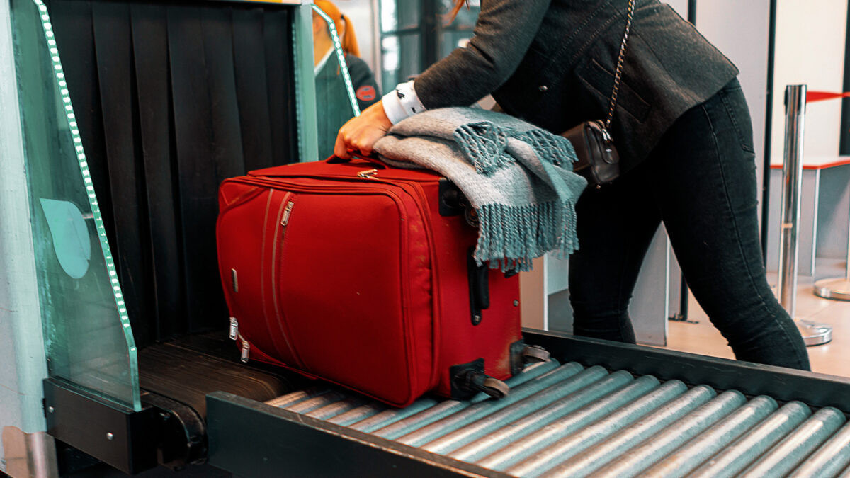 woman sending luggage through security