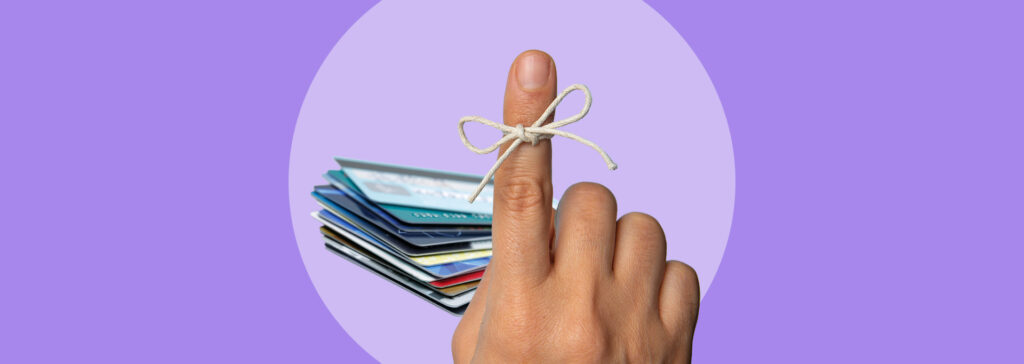 pile of credit cards next to finger with reminder string tied on it